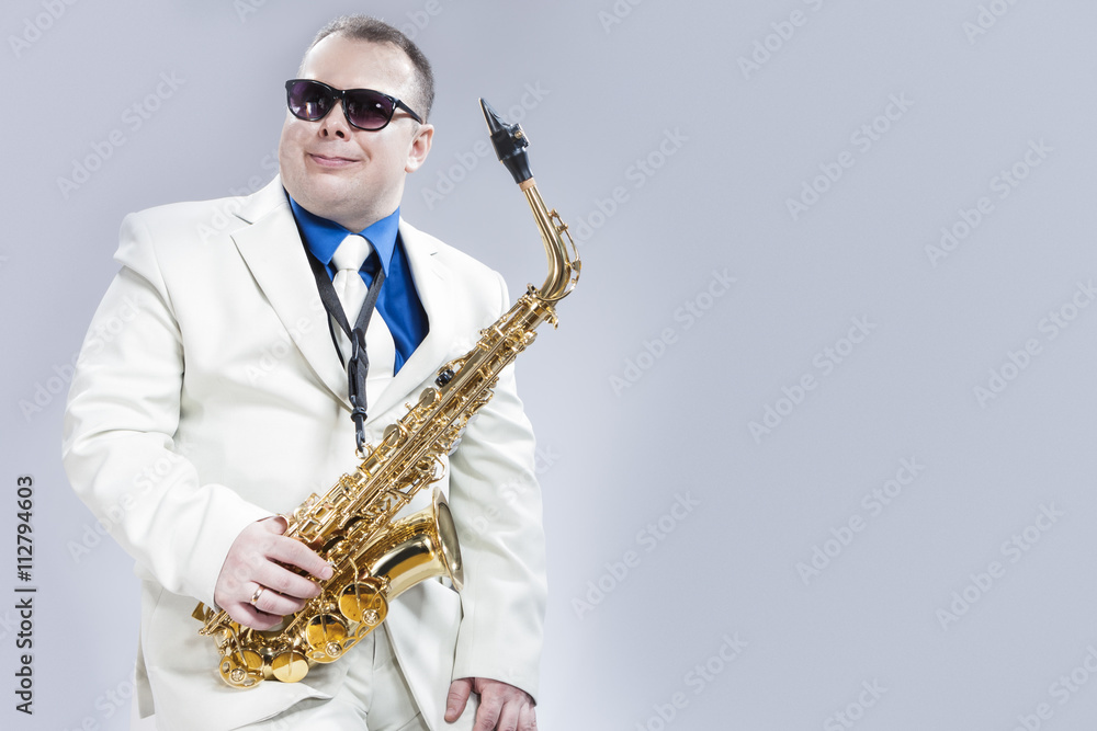 Fototapeta premium Portrait of Passionate Expressive Male Alto Saxophone Player in Sunglasses Against White