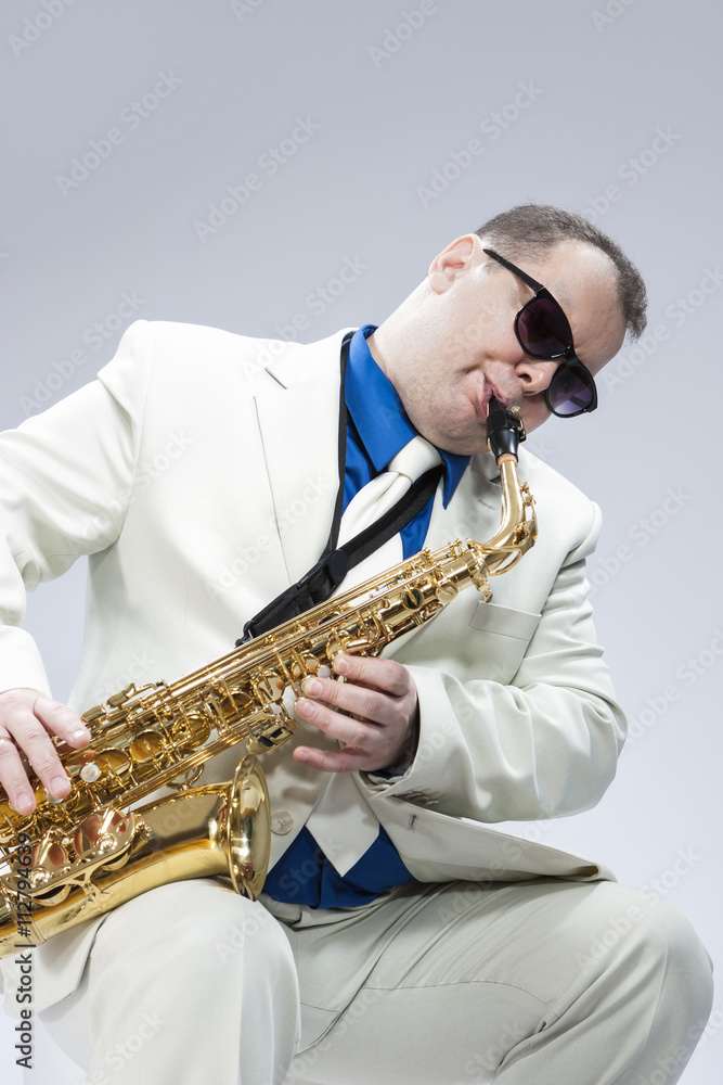 Fototapeta premium Caucasian Mature Male Musician Playing Alto Saxophone and Wearing Sunglasses