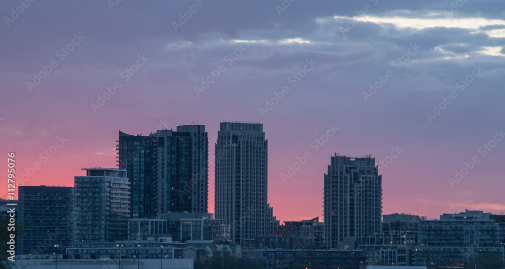 TALL BUILDINGS AGAINST A RED SKY AT SUNSET
