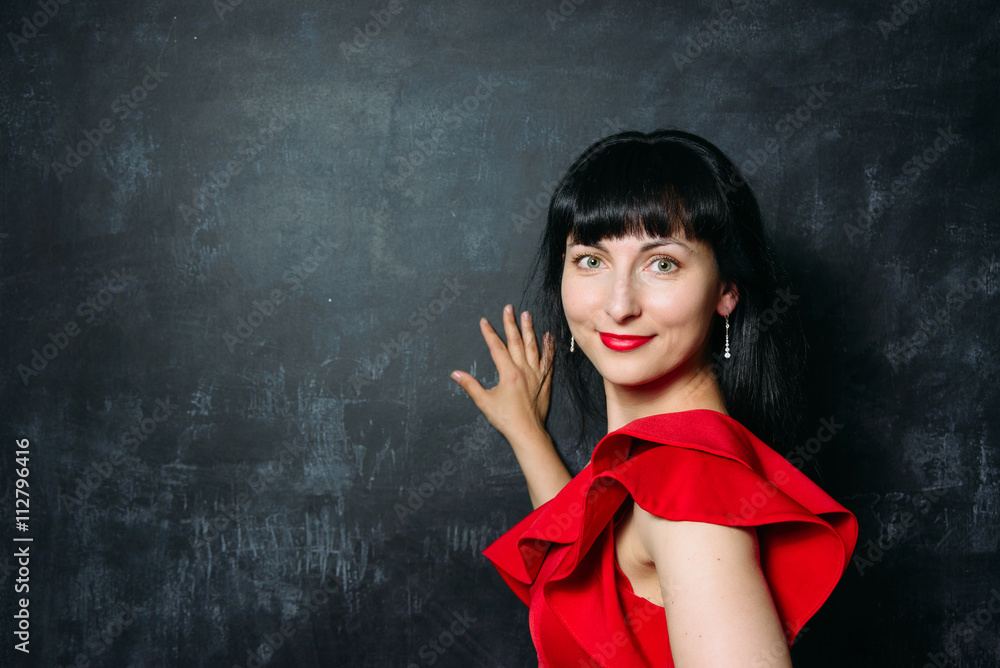 Beautiful young model woman in red dress posing over black slate