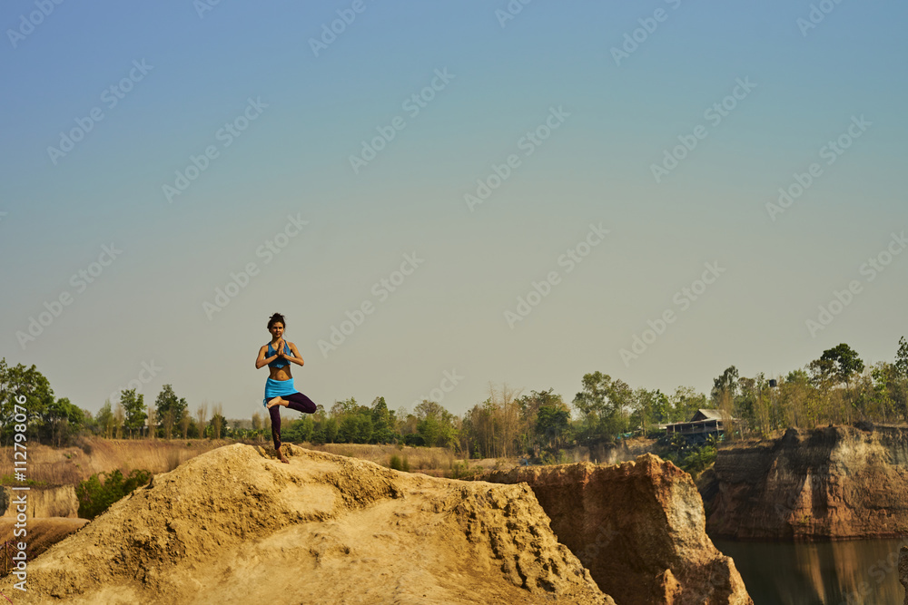 Skinny girl doing yoga on cliff