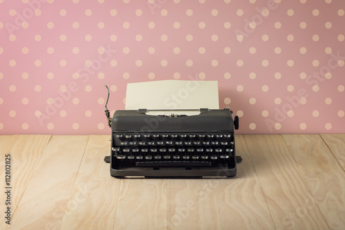 Image of vintage typewriter on pink polka dots wallpaper