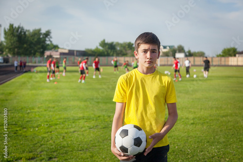 serious teenage boy with a soccer ball in his hand against the b © olezzo