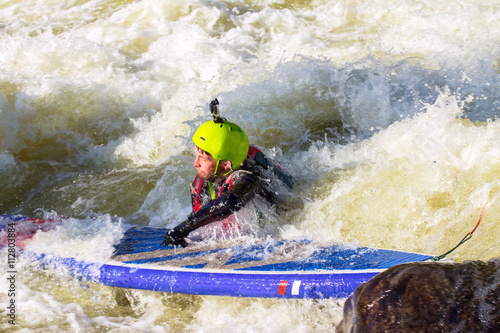 The man supsurfing on the rapids of the mountain river
