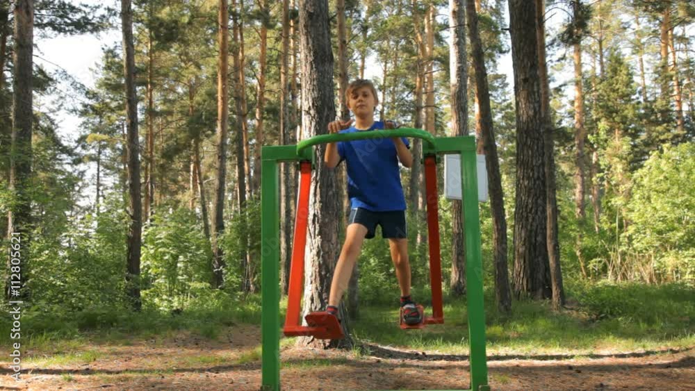 Young Boy doing fitness on gymnastic equipment on outdoor playground Young Boy doing fitness on gymnastic equipment on outdoor playground