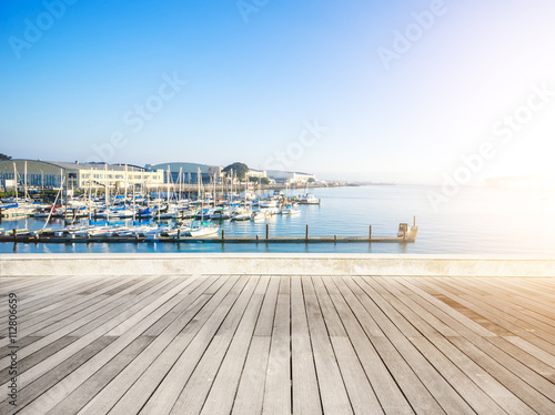 empty wood floor with sail boats on sea in sunny day