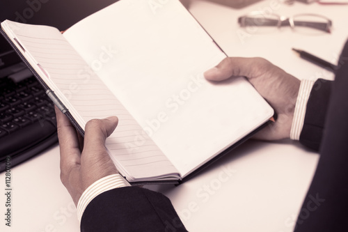 Businessman holding a notebook in office in vintage color tone