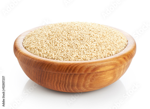 Wooden bowl with sesame seeds isolated on white background.