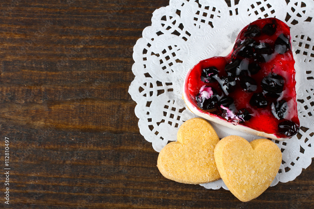 cake with cookies in the shape of a heart on a napkin or a brown wooden background cake with cookies in the shape of a heart on a napkin or a brown wooden background