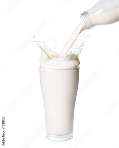 Pouring milk from bottle into glass with splashing., Isolated white background.