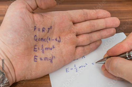 Student is cheating during exam with cheat sheet with formula written on hand. photo