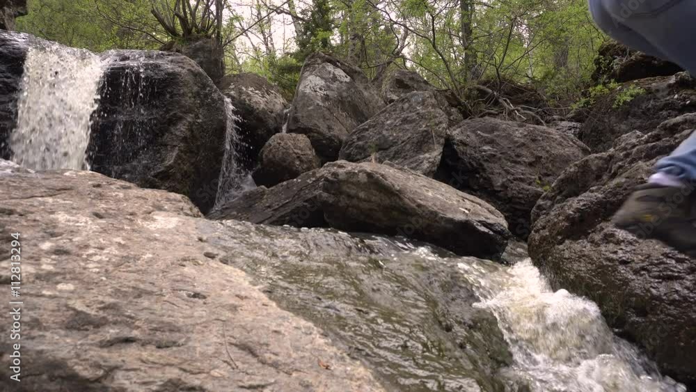 Couple Man and Woman Going Over a Mountain River to a Waterfall Summer Day Couple Man and Woman Going Over a Mountain River to a Waterfall Summer Day