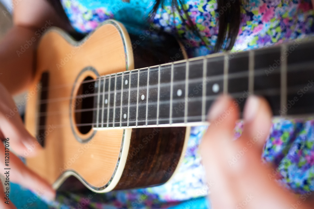 Obraz premium Close up of woman in flower print dress strumming ukulele