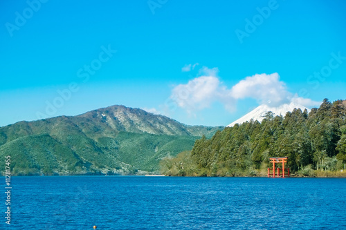 Red torii gate under lake Ashinoko with Mount Fuji under bright blue sunny sky in Hakone, Japan © voyata