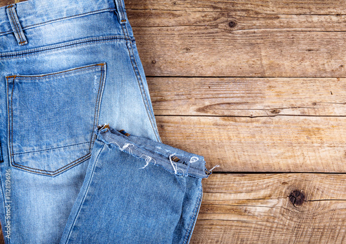 Stylish jeans folded on a wooden background. Clothing, fashion, lifestyle.