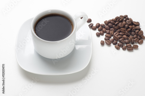 White coffee cup filled with black coffee and beans