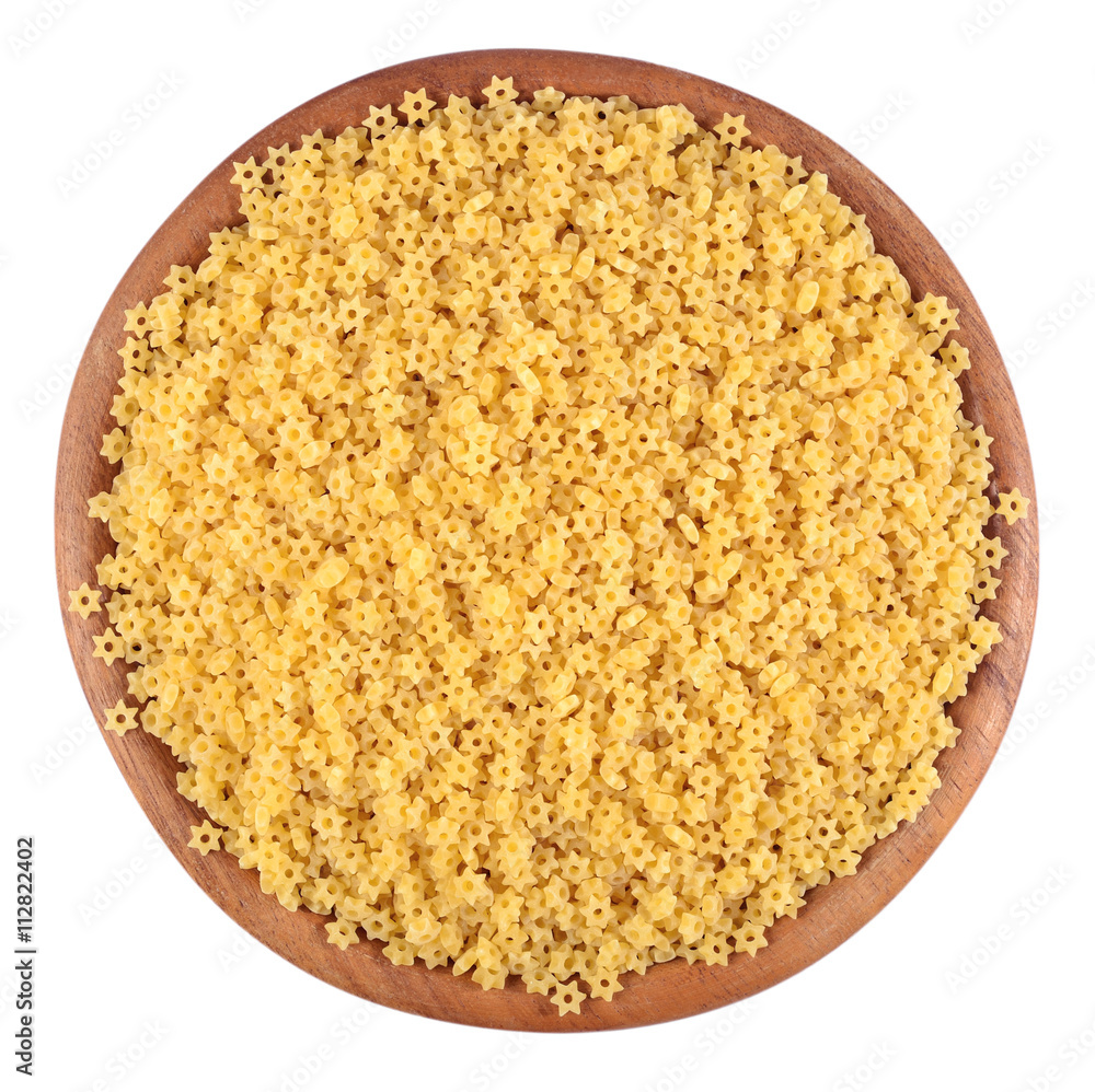 Uncooked italian pasta stars in a wooden bowl on a white Uncooked italian pasta stars in a wooden bowl on a white