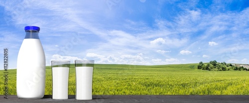 3D rendering of  milk glass bottle and glasses, with green fields and blue sky background.