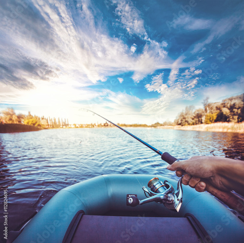 man fishing on a lake from rubber boat