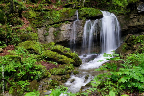 Kleiner Wasserfall im Wald mit Moos auf Steinen