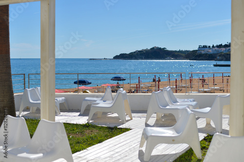 Beach view with restaurant chairs, blue sunny outdoors background seaside