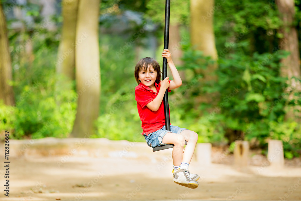 Cute child, boy, rides on Flying Fox play equipment in a childre