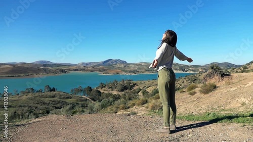 Young woman raising arms to the sky on the beautiful landscape with the lake, super slow motion
