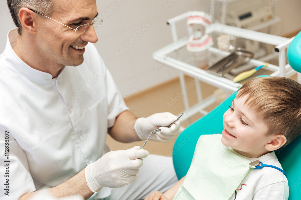 Smiling dentist doing dental treatment to little boy Smiling dentist doing dental treatment to little boy