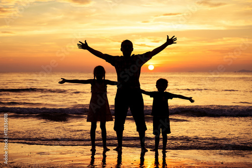 Father and children playing on the beach at the sunset time.