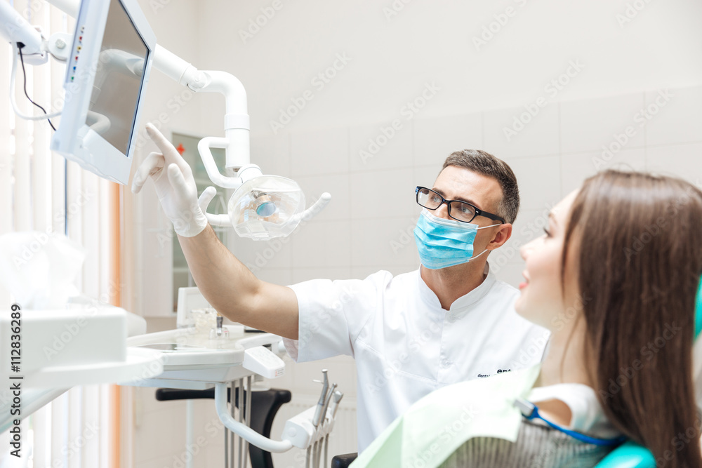 Dentist explaining x ray picture to patient on led monitor Dentist explaining x ray picture to patient on led monitor