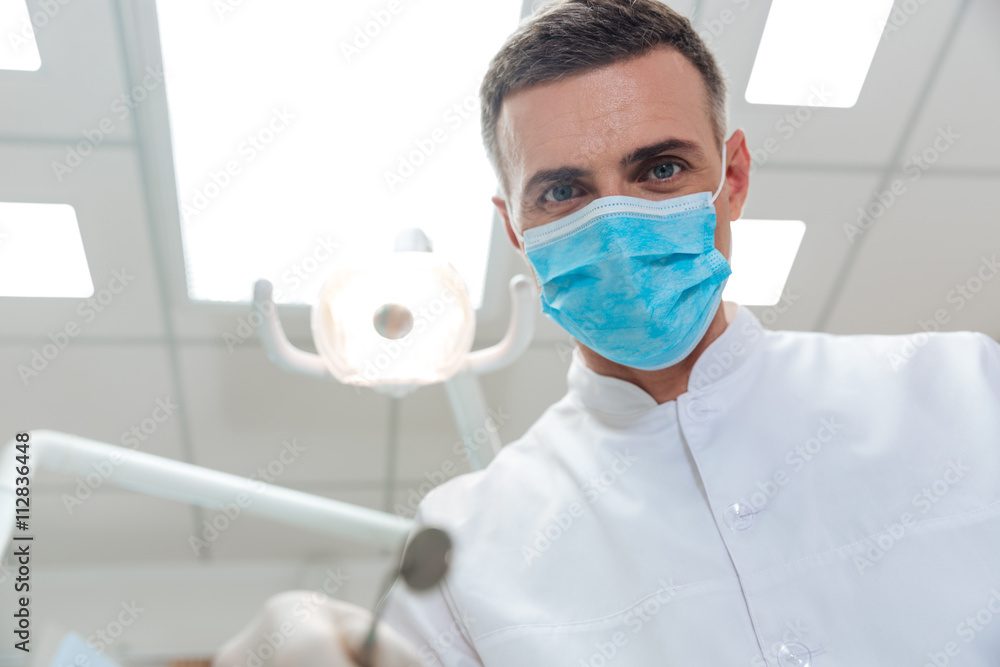 Fototapeta premium Male dentist making treatment looking at camera