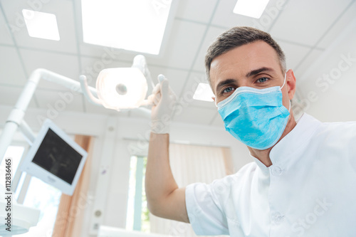 Male dentist looking at camera in dental office photo