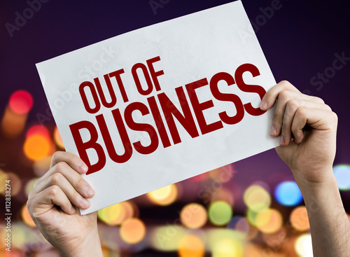 Out Of Business placard with night lights on background