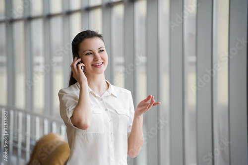 Young businesswoman talking on mobile phone while standing by wi