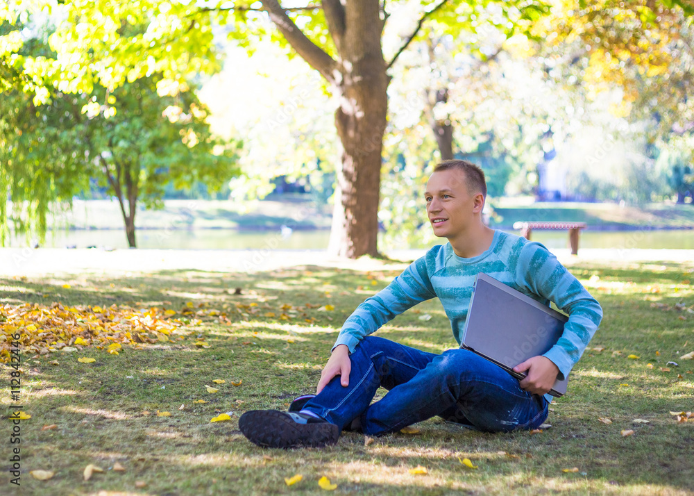 Student using his laptop in autumn city park Student using his laptop in autumn city park
