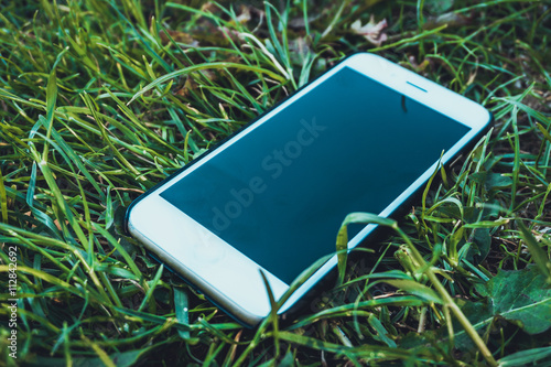 Blank mobile phone lying in green grass photo