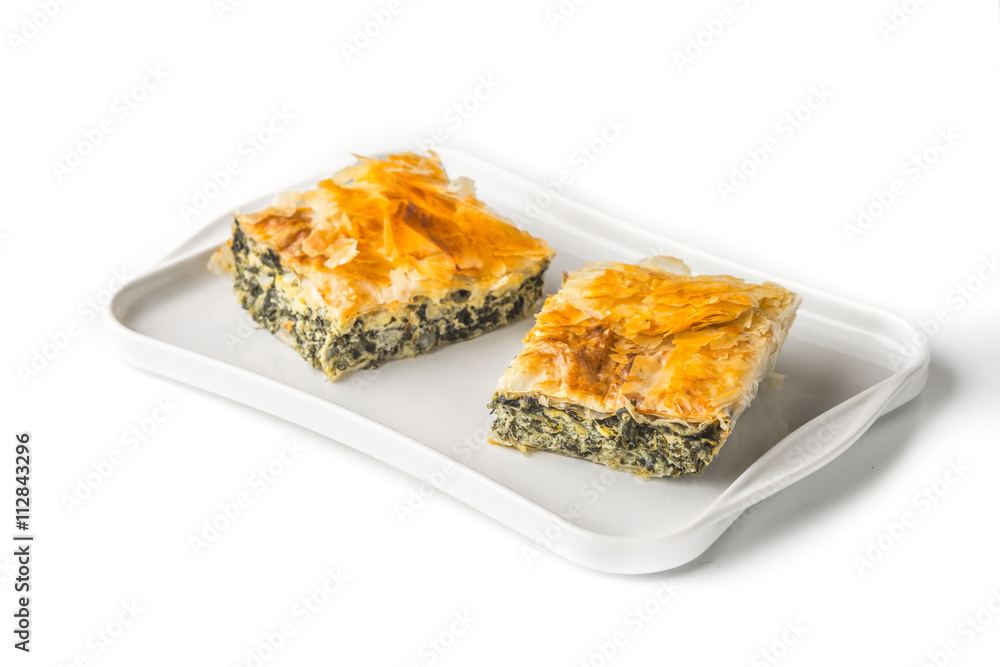 Piece of Greek pie spanakopita on the white plate on the white background Piece of Greek pie spanakopita on the white plate on the white background