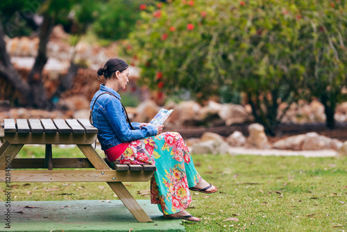 Woman sitting at table in garden reading folder. Botanicactus. M photo