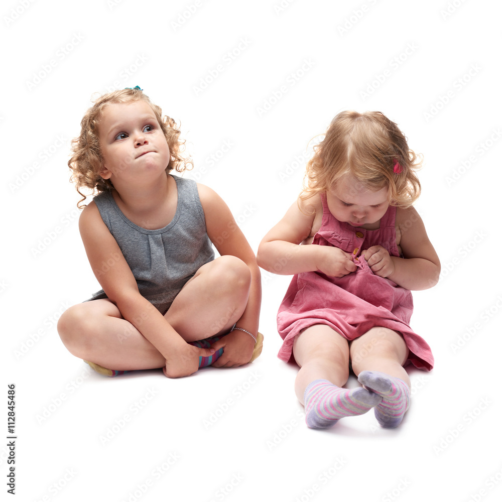 Couple of young little girl sitting over isolated white background Couple of young little girl sitting over isolated white background