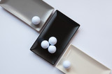 Different ceramic dishes with golf balls on over white backgroun