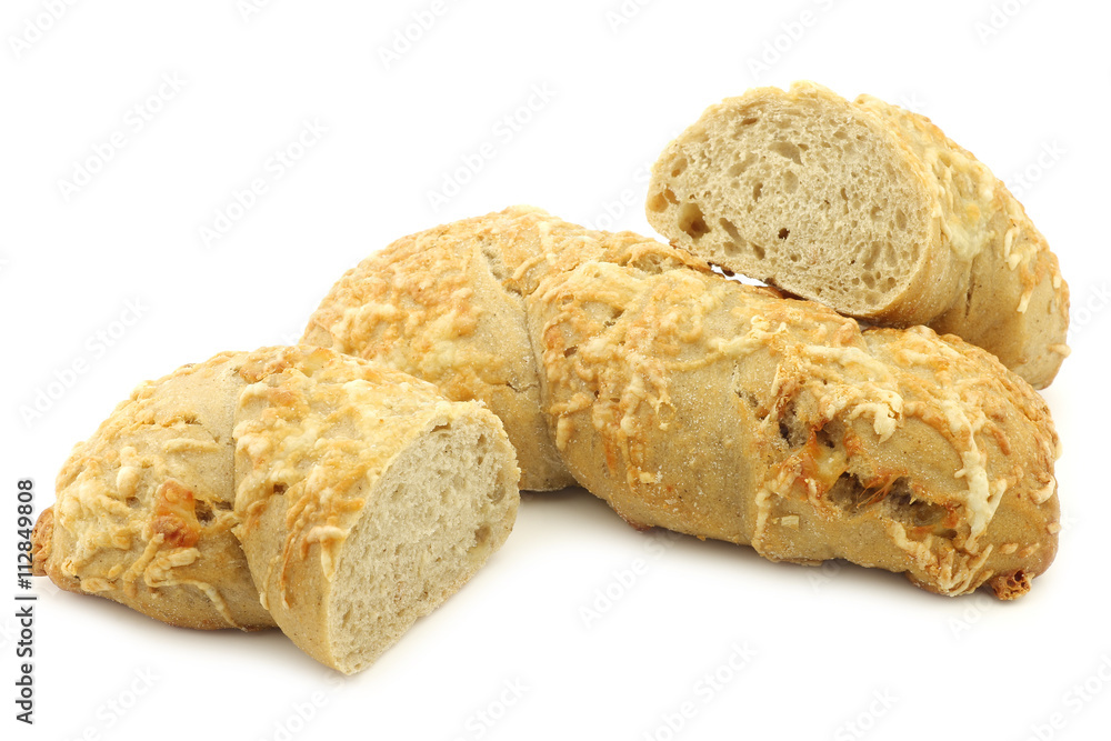 freshly baked spelt bread covered with grated cheese and a cut one on a white background