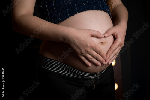 Pregnant woman making heart shape on her bump.