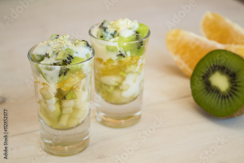 fruit, kiwi, orange and pear in small cups on a light background