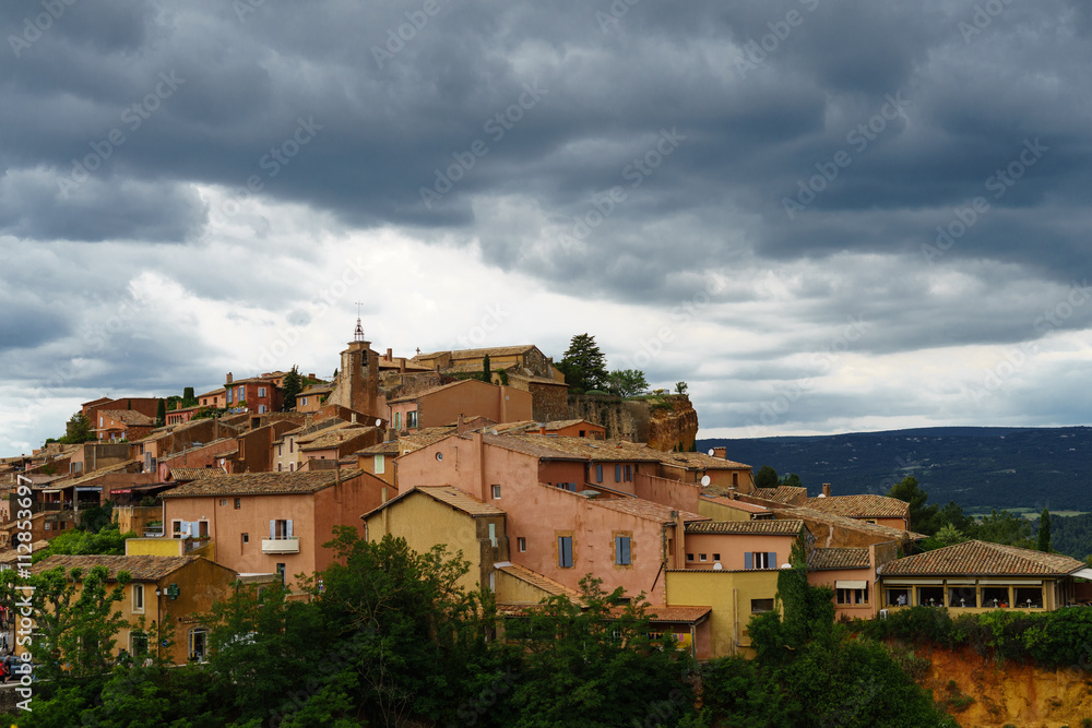 F, Provence, leuchtender, dramatischer Wolkenhimmel über den markanten Häusern von Roussillon