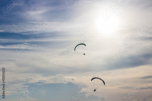 Silhouette men flying with paramotor in the blue sky
