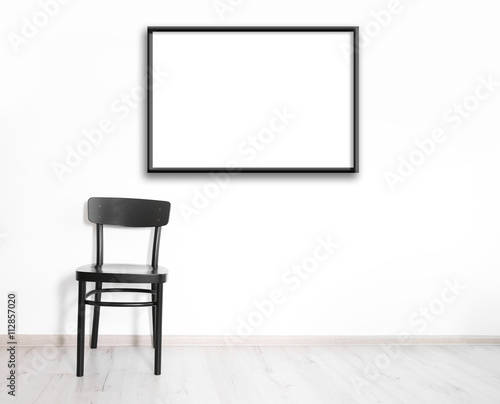 Fototapeta Naklejka Na Ścianę i Meble -  Black chair and empty picture frame on wall background