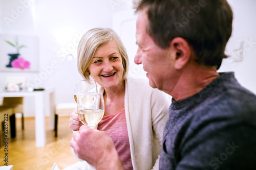 Senior couple sitting in living room, drinking champagne