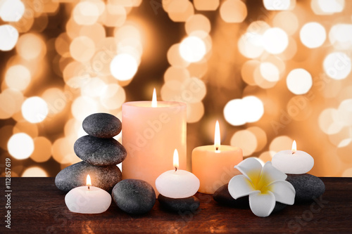 Spa stones with burning candles and flowers on festive background