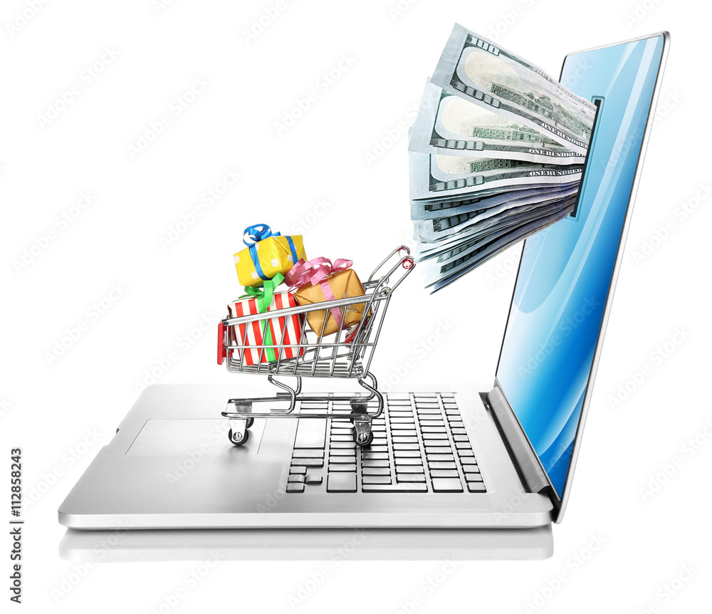 Online shopping concept. Laptop with money from monitor screen and small shopping cart full of gifts isolated on white background