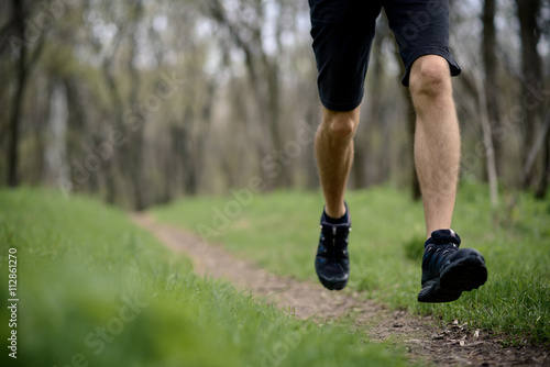 Young Sportsman Running on the Spring Forest Trail in Morning. Legs Close up View